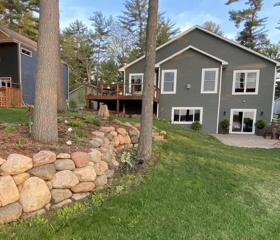 Residential boulder retaining wall with landscaping on a sloped lakefront lot near Forest Lake, MN